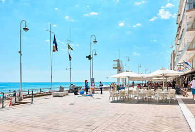 People at promenade by sea against sky