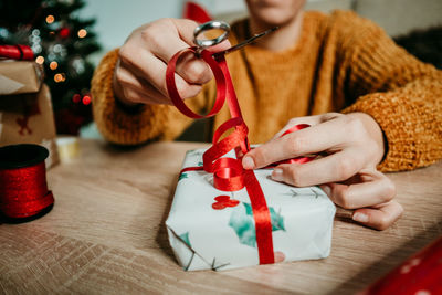 Midsection of woman packing christmas gift at home