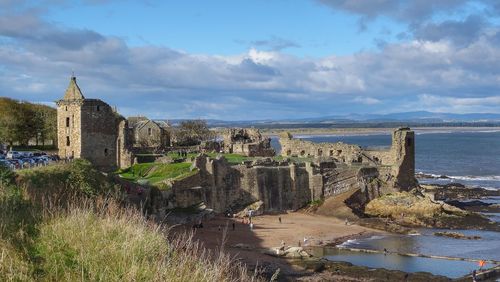 Old ruin building at coastline against cloudy sky