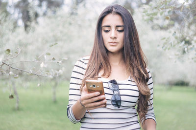Portrait of beautiful young woman using mobile phone outdoors