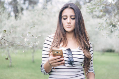 Beautiful young woman using mobile phone outdoors