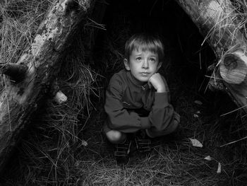 Thoughtful boy crouching in hut