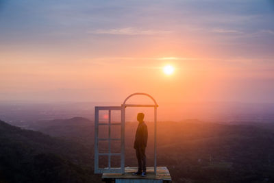 Man standing on mountain against sky during sunset