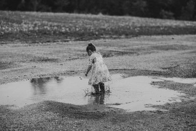 Full length of girl splashing water from puddle at beach