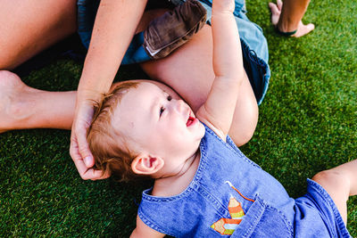 High angle view of baby lying on grass