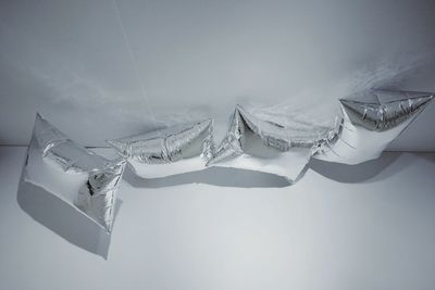 Low angle view of helium balloons against white wall