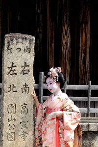 Woman standing with cross against the wall