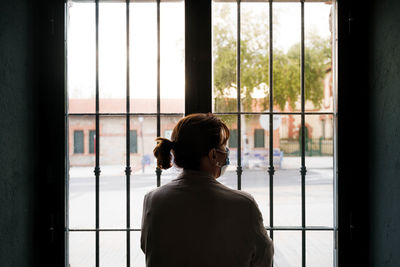 Rear view of woman looking through window