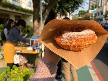 Cropped hand holding food in city 