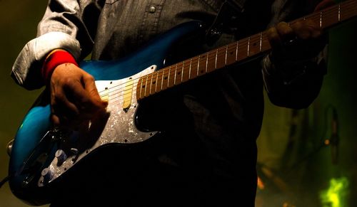 Midsection of man playing guitar