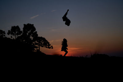 Silhouette woman flying against sky during sunset