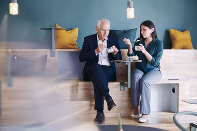 Full length of businessman and businesswoman eating at office cafeteria