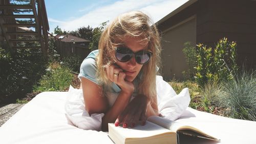 Woman reading book while sitting in yard