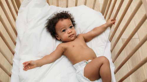 High angle view of cute baby boy lying in crib at home