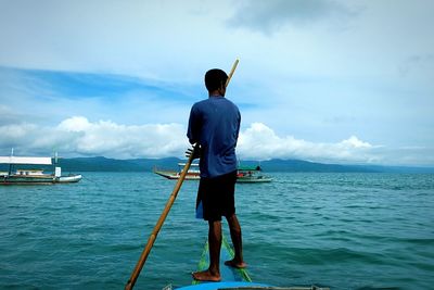 Rear view of man standing on sea against sky