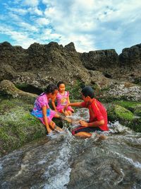 Rear view of women on rock against mountains against sky