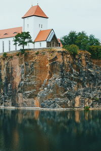 Houses by lake and buildings against sky