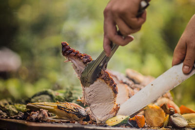 Slicing roasted pork in summer garden 