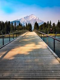 Footbridge leading to mountains against sky