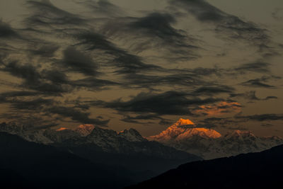 Scenic view of snowcapped mountains against cloudy sky during sunset