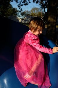 Full length of girl on blue slide at park during sunny day