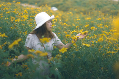 Woman with yellow flowers on field