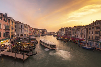 Boats moored in city at sunset