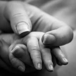 Close-up of mother holding hand of baby 