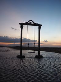 Lifeguard hut on beach against sky during sunset