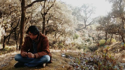 Young man sitting in forest