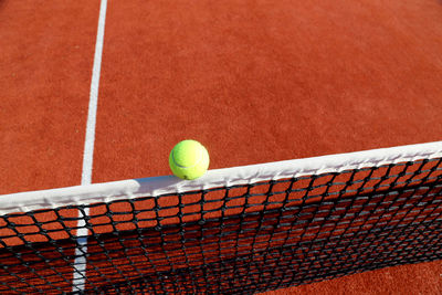 High angle view of yellow ball on net at tennis court