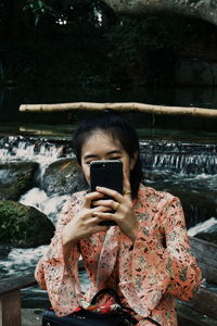 Close-up of woman taking selfie against waterfall