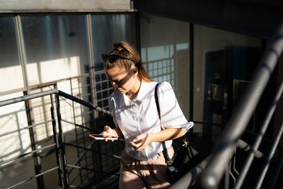 Woman looking at camera while standing on railing