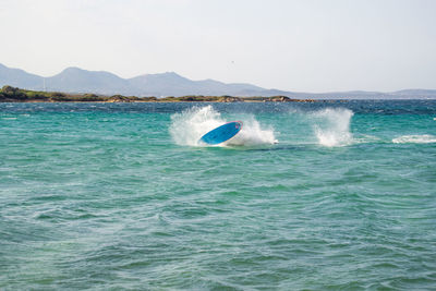 Scenic view of sea against clear sky with a windsurfer just fallen in the water