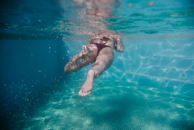 Mid adult woman swimming underwater in pool