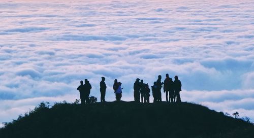 Silhouette people standing on mountain against sky