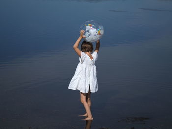 Rear view of woman standing by lake