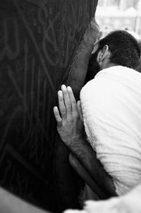 Rear view of man leaning on by mosque wall at mecca