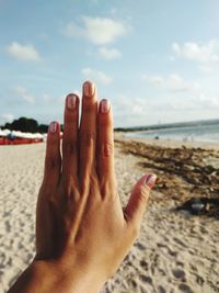 Cropped hand of woman showing painted fingernails at beach