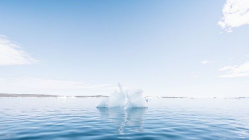 View of iceberg on water surface against sky