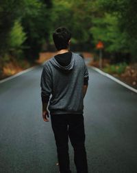 Rear view of man walking on road in forest