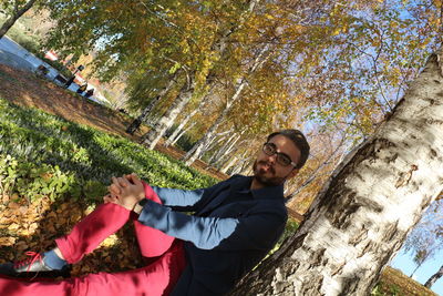 Low angle portrait of man with arms raised against trees