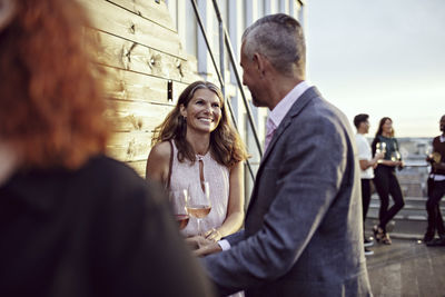 Smiling businesswoman talking with coworkers in party on terrace
