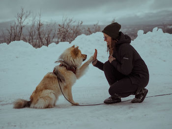 Low section of man with dogs on snow covered field