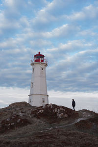 Low angle view of man by lighthouse against sky