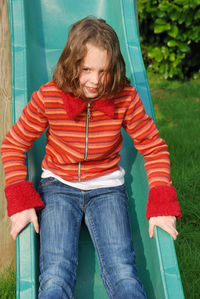 Girl sitting on slide in playground