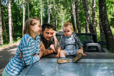 Mom, dad and little son in a convertible car. summer family road trip to nature