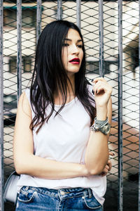 Beautiful woman looking away while standing against gate