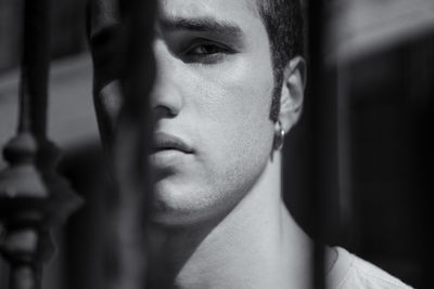 Close-up portrait of young man against fence