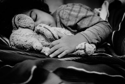 Close-up of girl with toy sleeping on bed at home